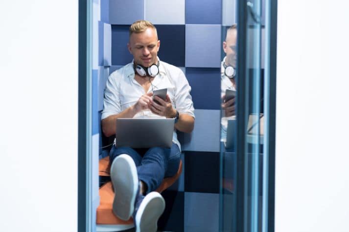 innovatives Konferenzsponsoring, das einen Mann zeigt, der in einer Privatkabine sitzt und auf sein Mobiltelefon schaut.